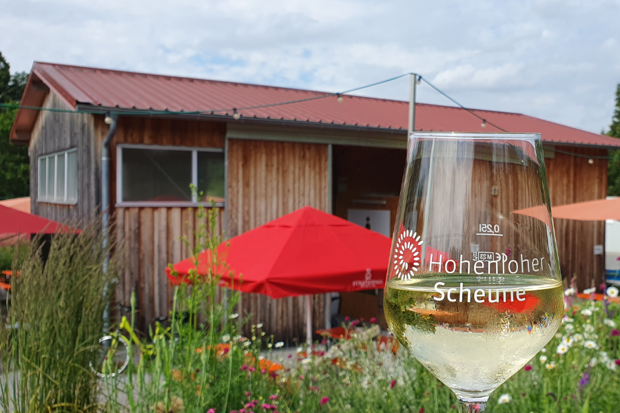 Foto: Weißweinglas vor Hohenloher Scheune und rotem Sonnenschirm